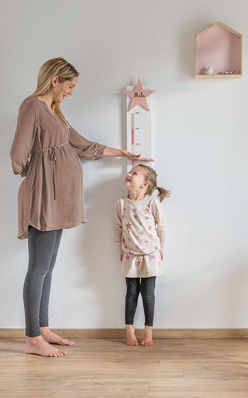 Une maman mesure sa fille à l'aide d'une toise L'atelier des Poulettes